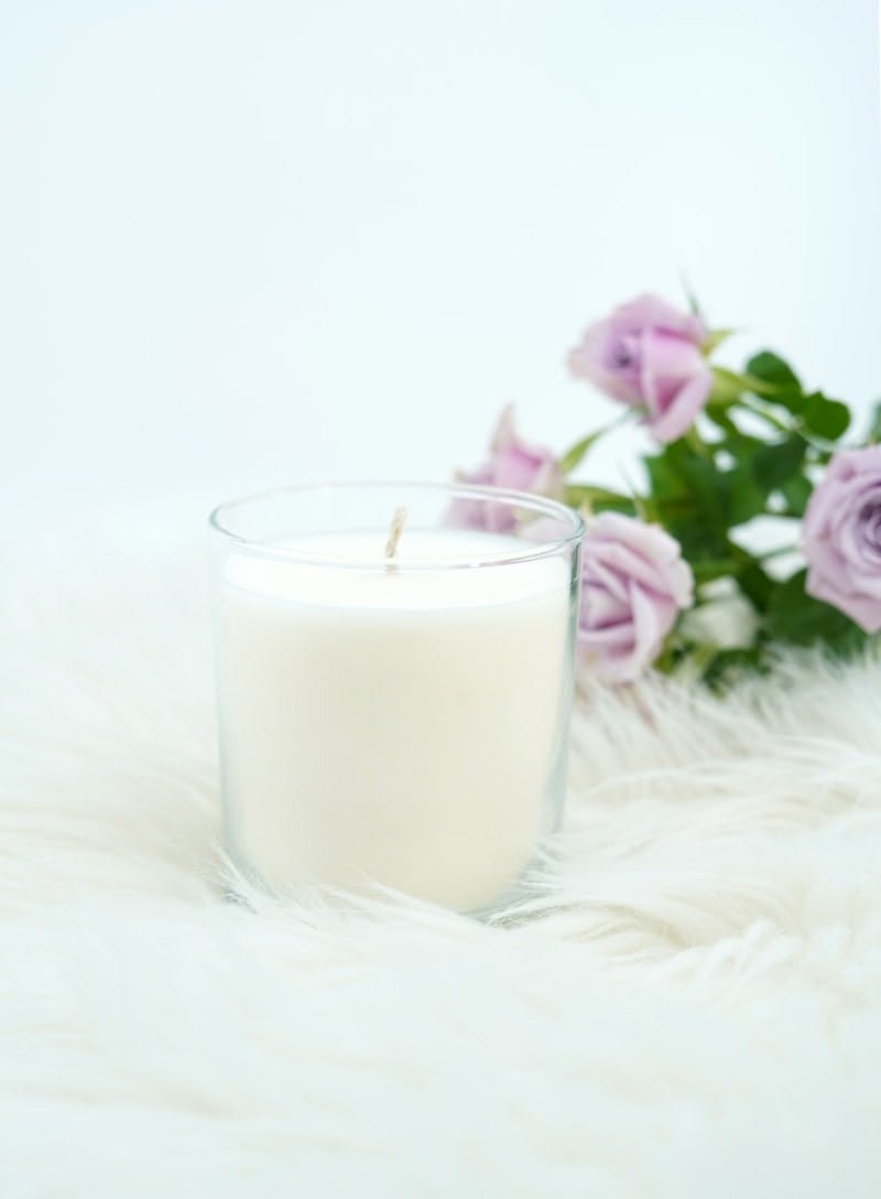 white pillar candle on white fur textile