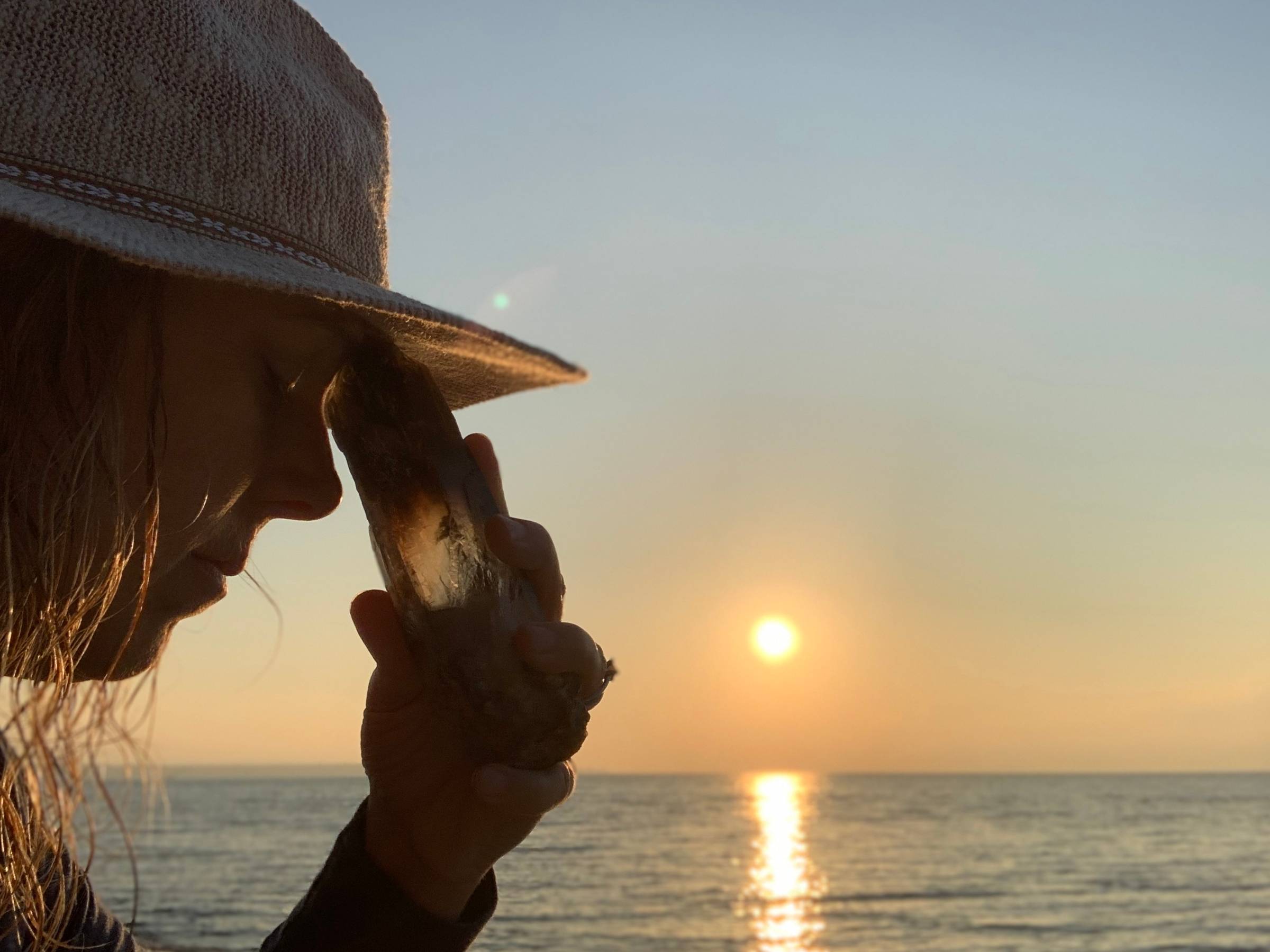 Smoky quartz crystal resting at the forehead in front of a Lake Superior sunset