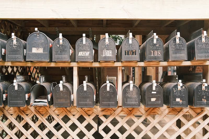 Rows of old black mailboxes on wooden shelves.