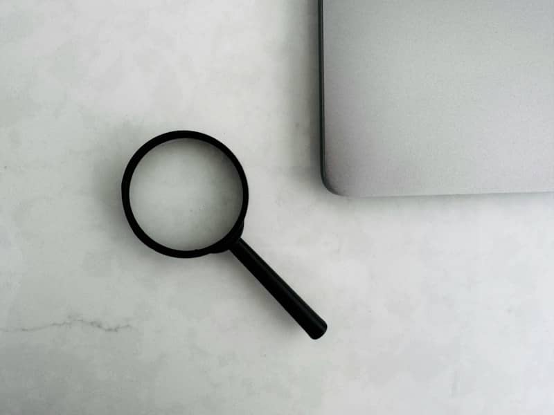 Magnifying glass sits near a laptop on a table.