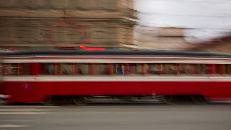 A blurry red trolley moves down the street.