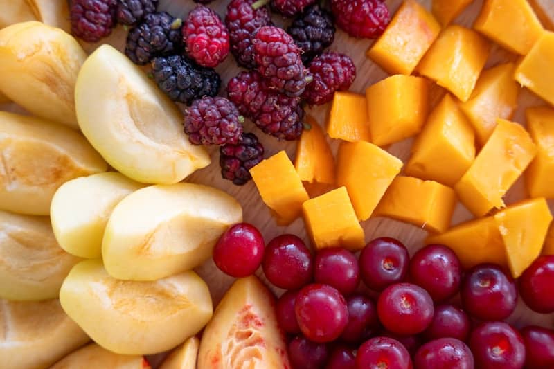 Sliced apples, mulberries, diced mango, and red grapes.