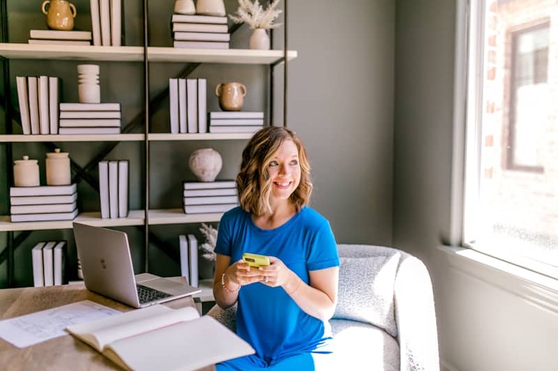Woman in blue dress sitting at desk with laptop.