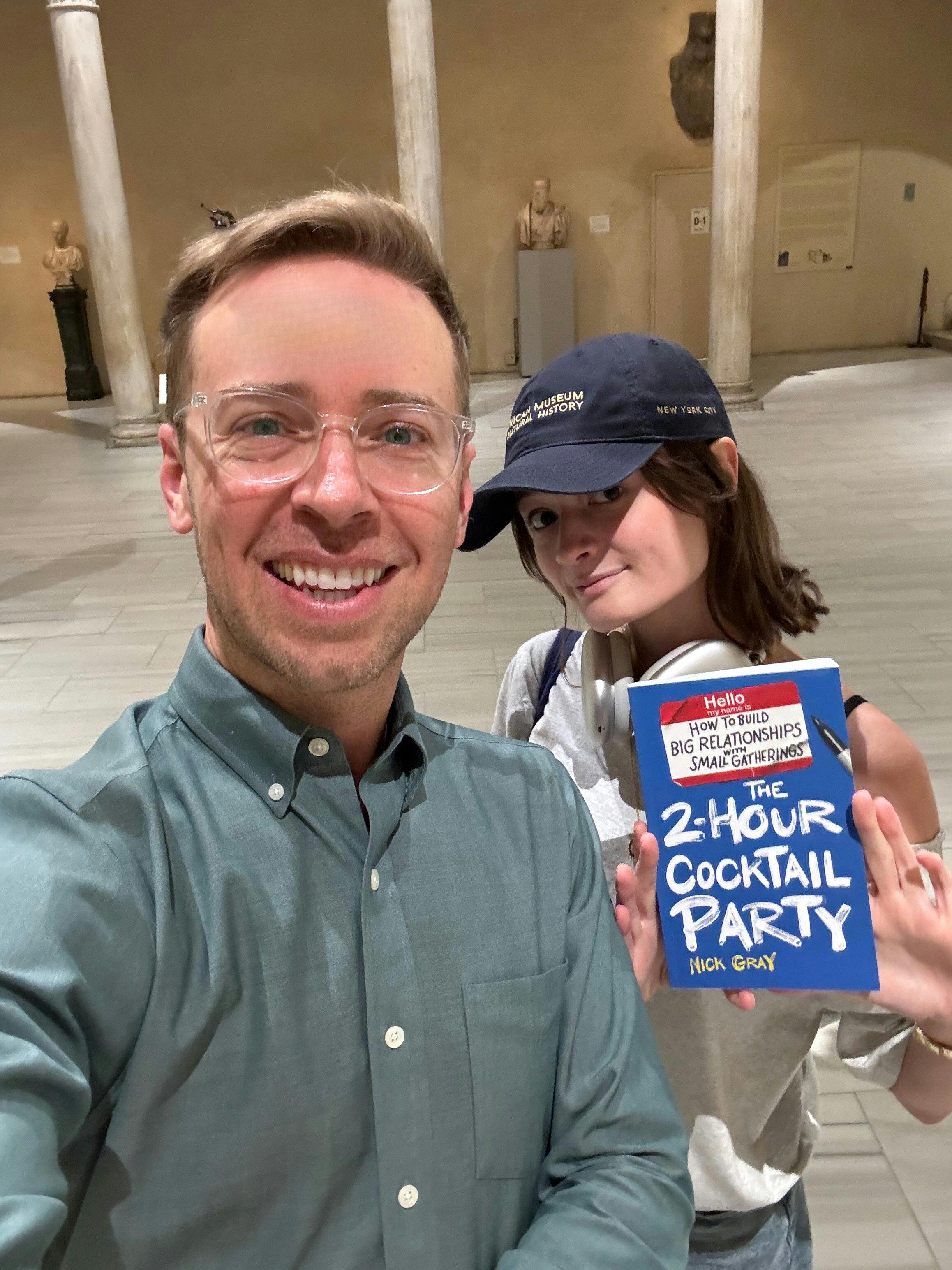 A selfie of Nick Gray and his friend Caitlin while holding his book The 2-Hour Cocktail Party