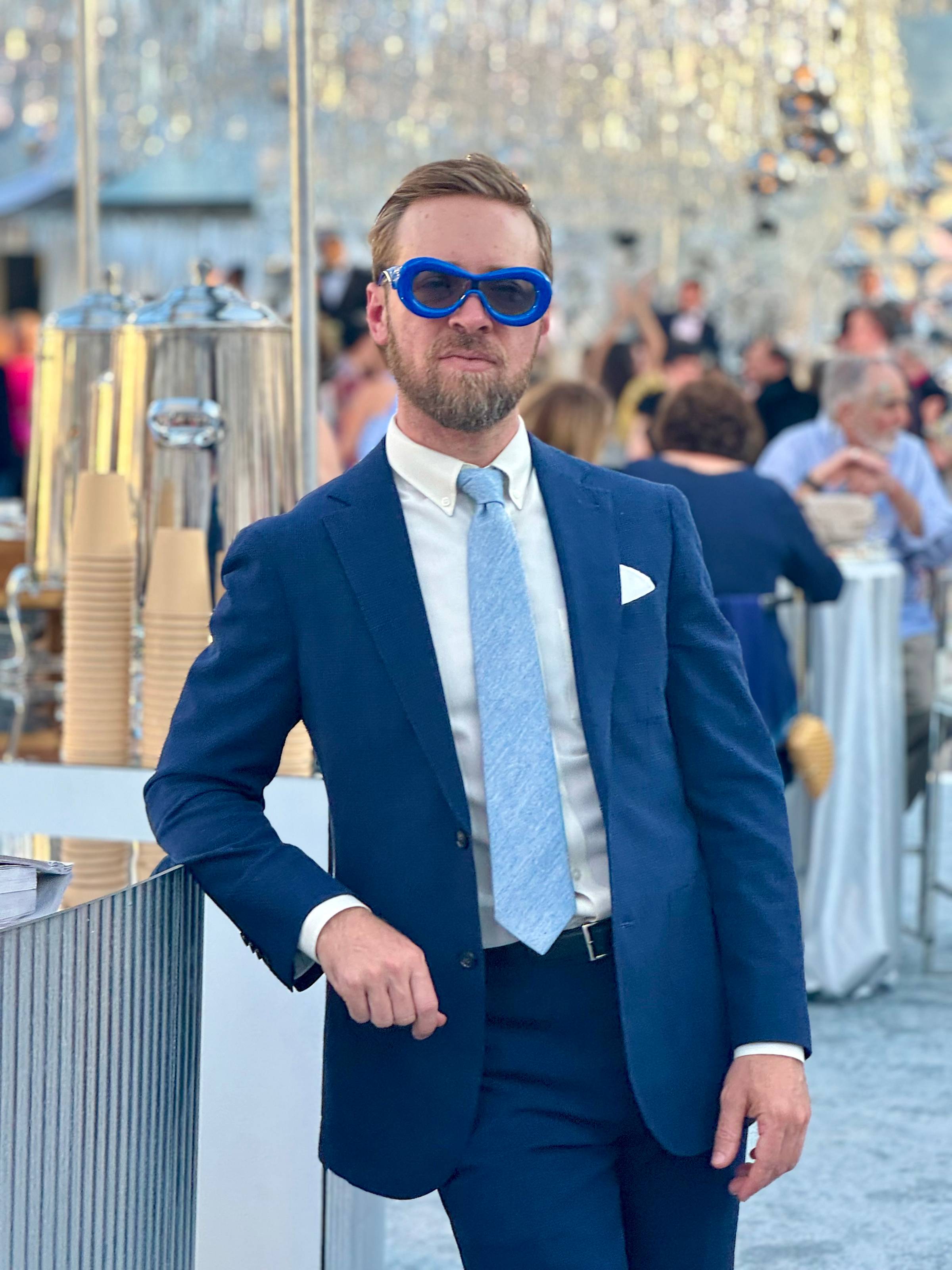 Nick Gray wearing blue tuxedo and blue funky glasses at a wedding