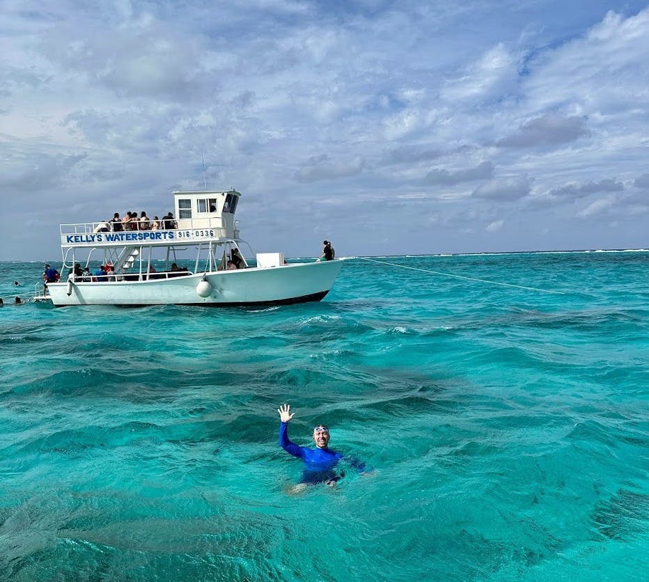 a photo of Nick Gray swimming in Cayman Islands with a boat behind him