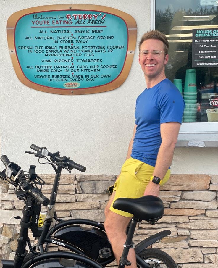 photo of Nick Gray riding a bike wearing blue shirt and yellow shorts