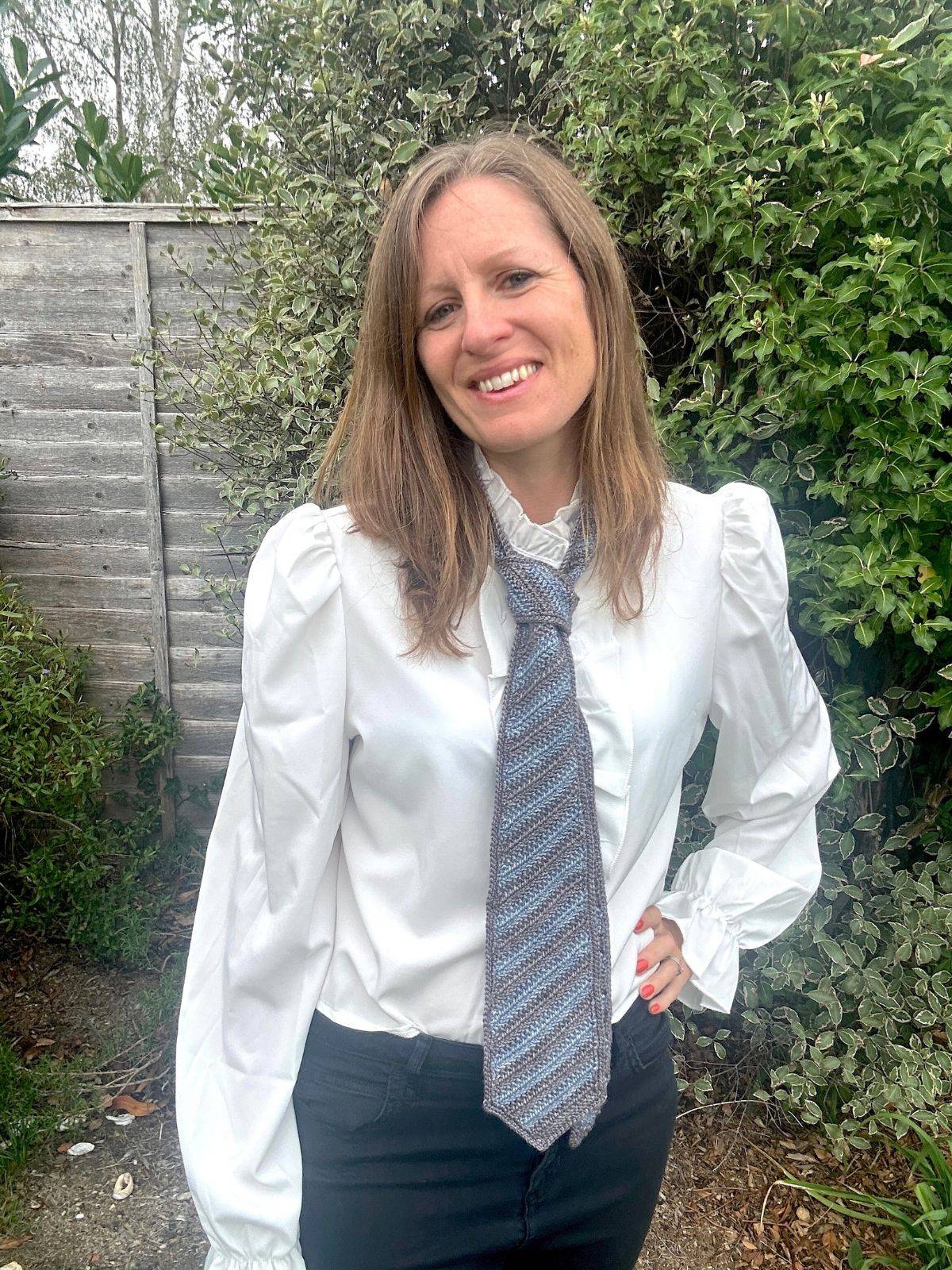A woman wears a grey and blue crochet tie