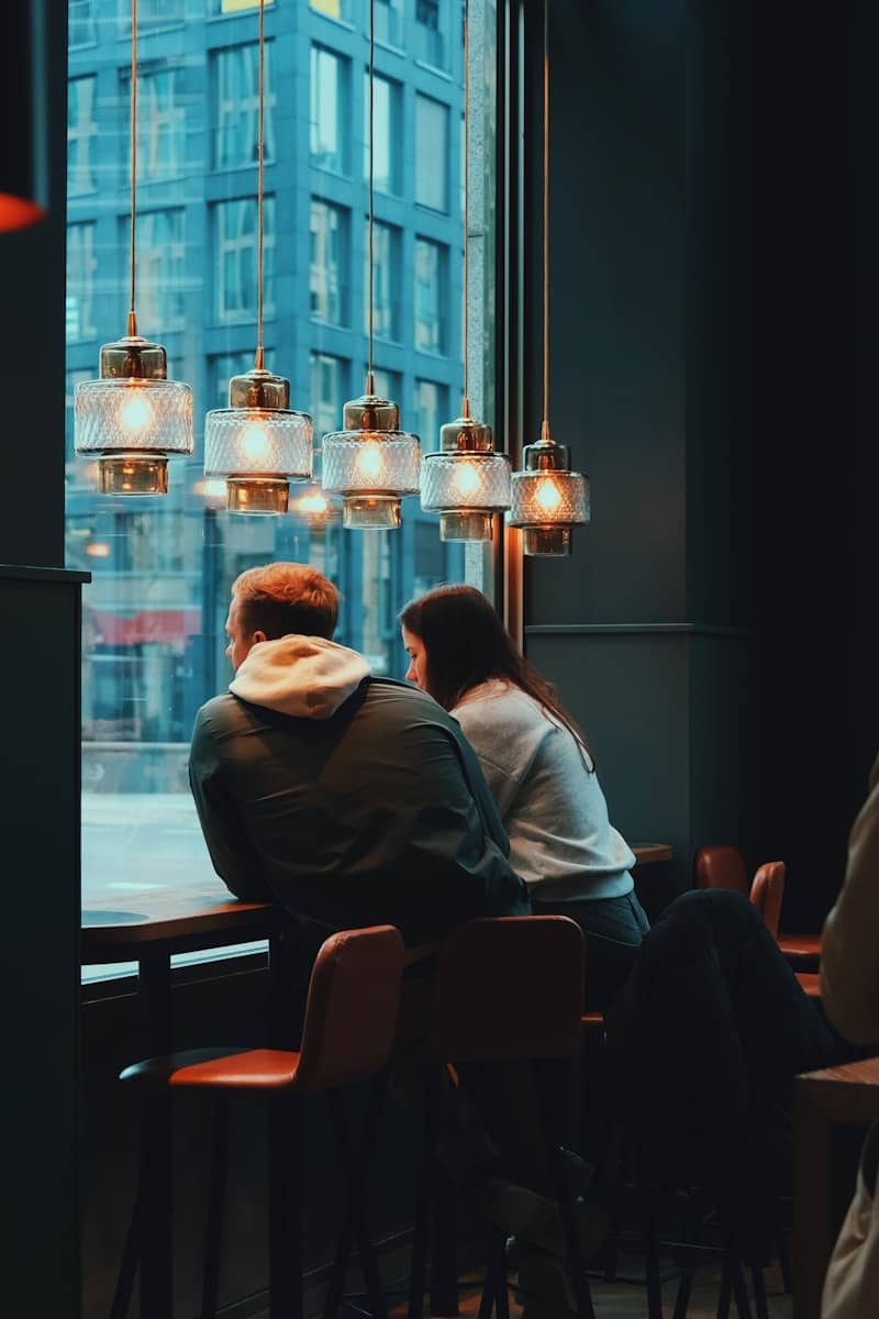 two people sitting at a table looking out a window