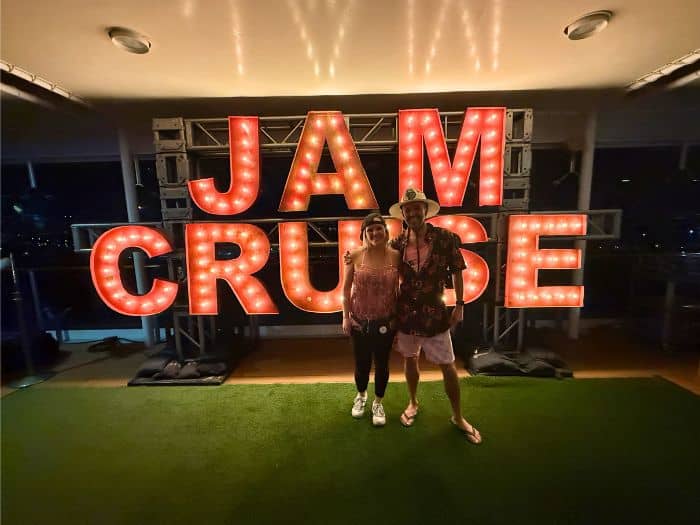 Rachel and Sasha in front of the brightly lit Jam Cruise sign on the boat