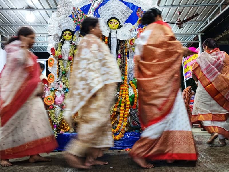 Women in traditional attire near a durga idol