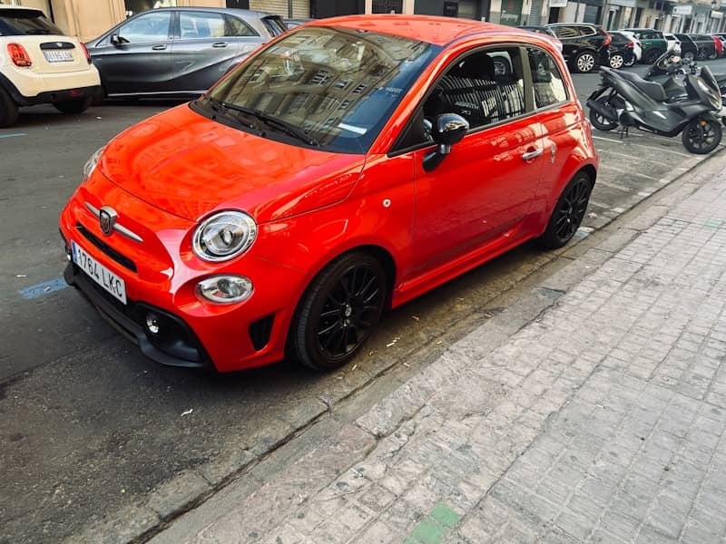 A red fiat 500 abarth parked on the street.