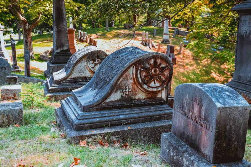Old, weathered tombstones in a grassy cemetery.