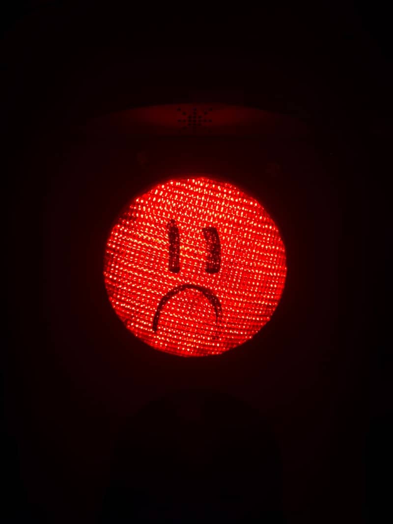 A red light with a sad face drawn on it.