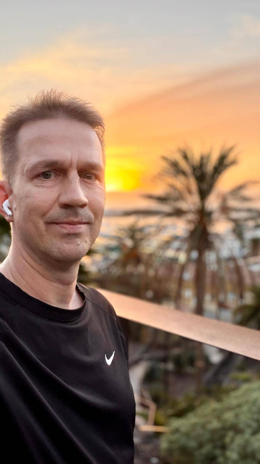 ein Mann vor einem Sonnenuntergang mit Palmen im Hintergrund