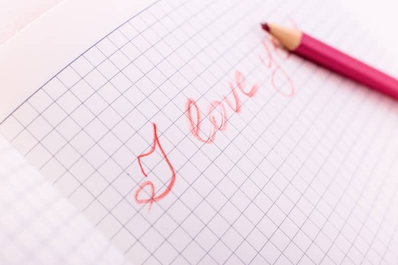 a red pencil writing the word love on a piece of paper