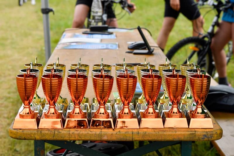 A row of shiny copper trophies on a wooden table.
