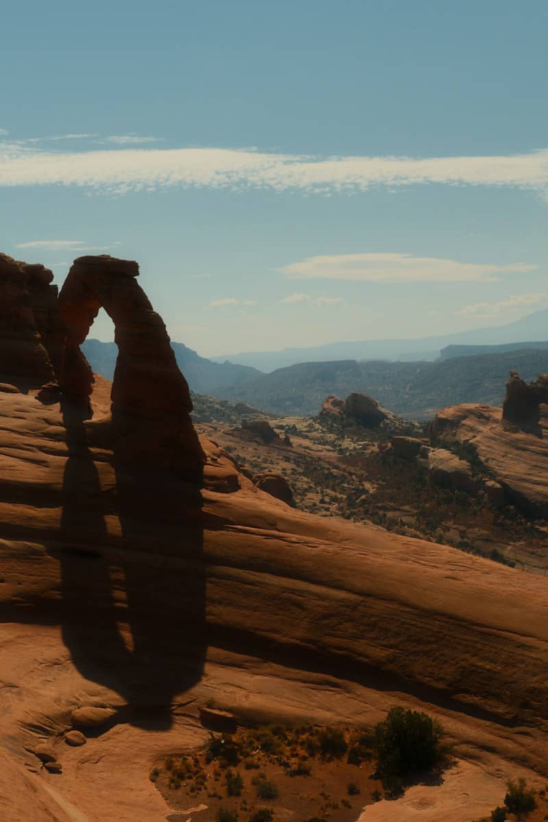 Delicate Arch casting a long shadow over the red sandstone landscape in Arches National Park