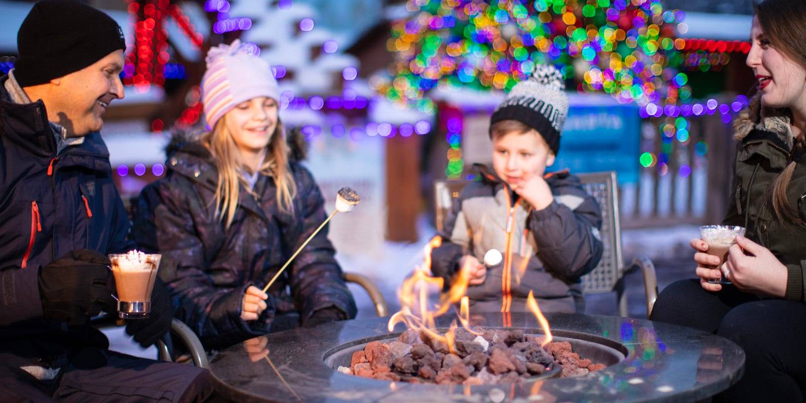 family gathers around a gas fireplace outside at Winter on the Mountain