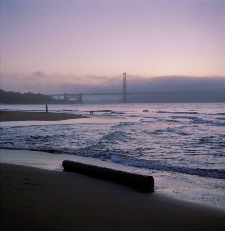 Beach scene with a bridge in the background.