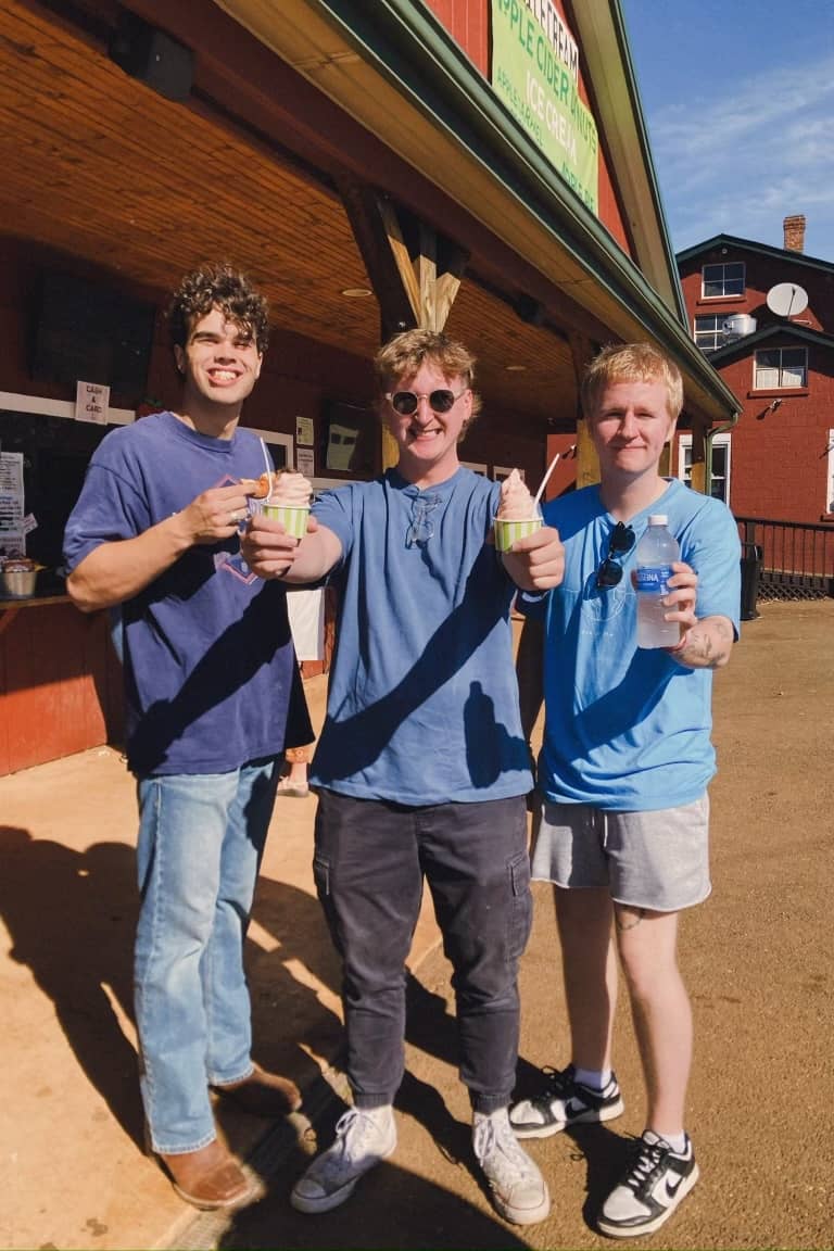 Three young adults eating ice cream and cider donuts outside