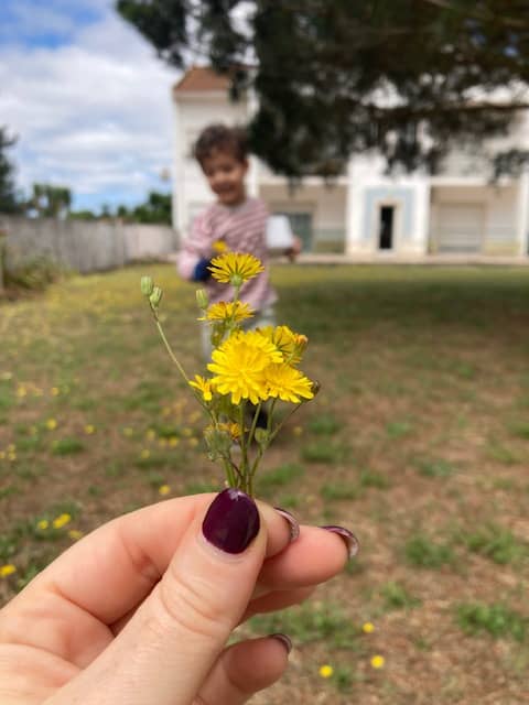 yellow flowers held in a woman's hand, little boy running out of focus