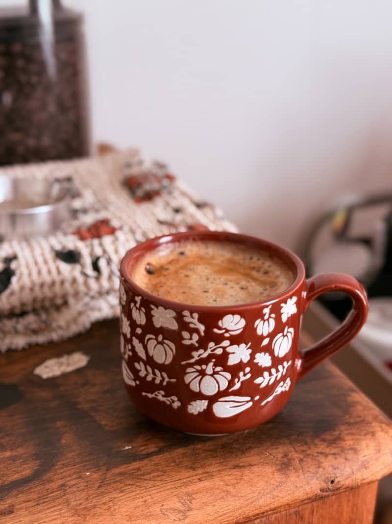 A festive mug filled with coffee sits on a wooden surface.