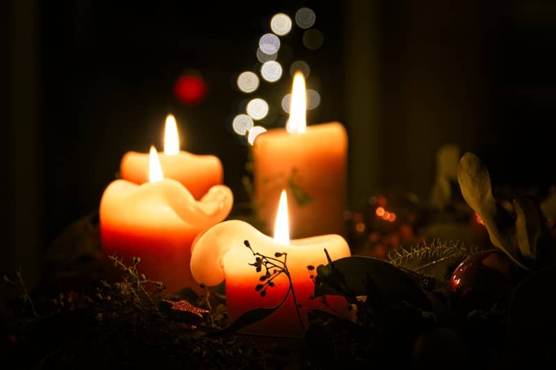 Four lit candles with bokeh lights in background