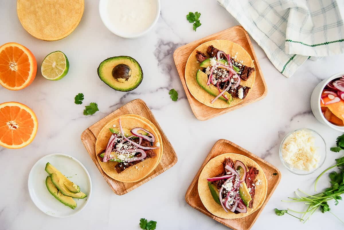 skirt steak tacos with toppings on marble countertop
