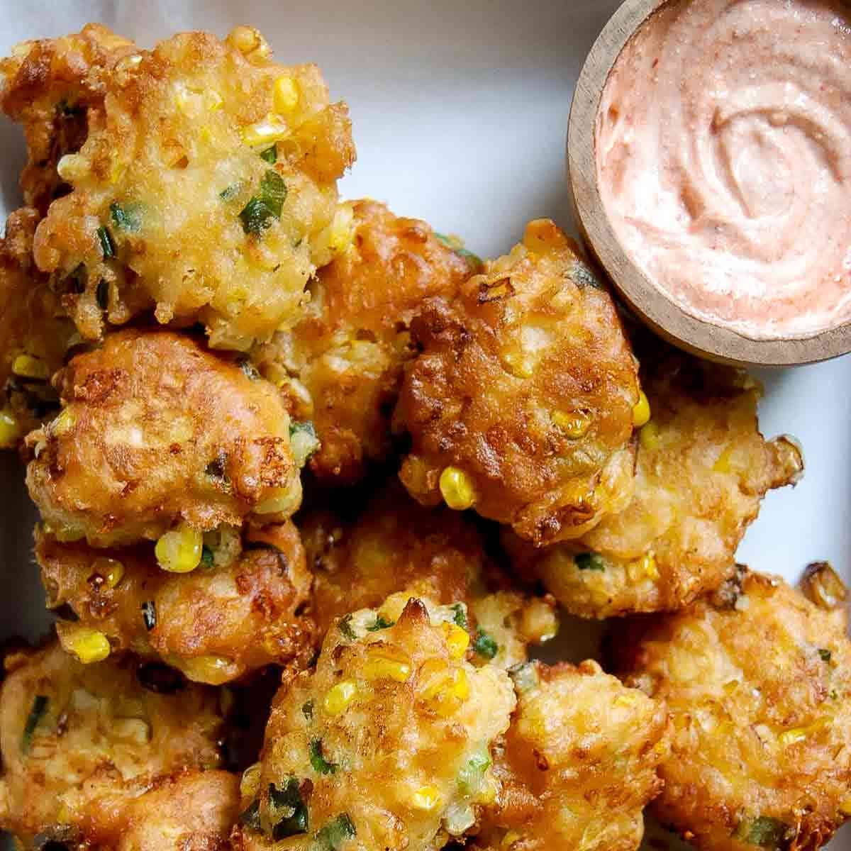 crispy corn nuggets on a tray with a dipping sauce on the side. 