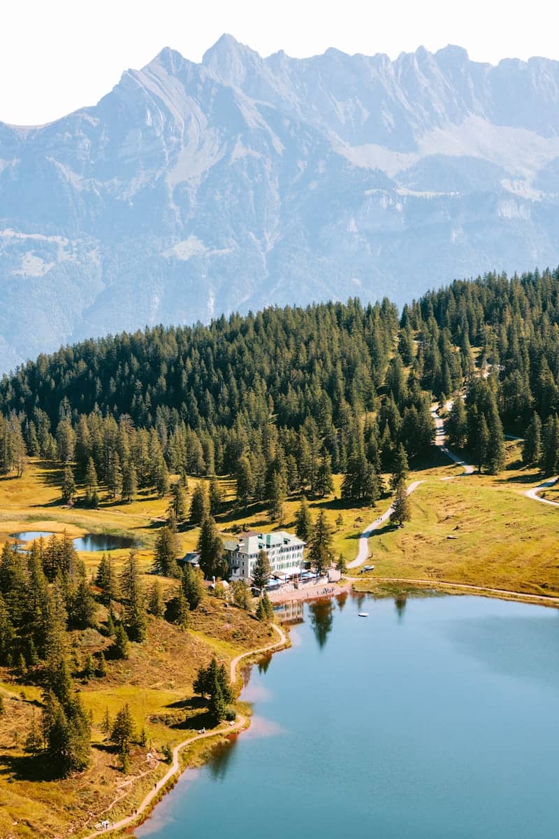 Hotel nestled by a serene lake with mountains behind