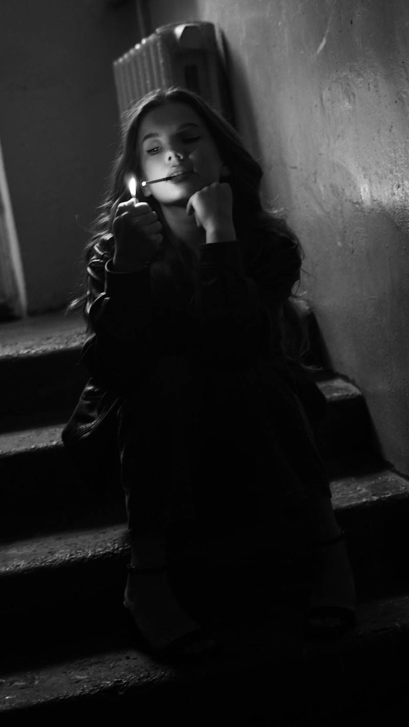 Young woman lighting a cigarette on stairs