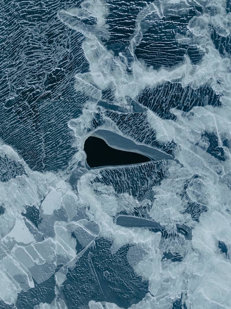 Abstract pattern of ice with dark water pockets.