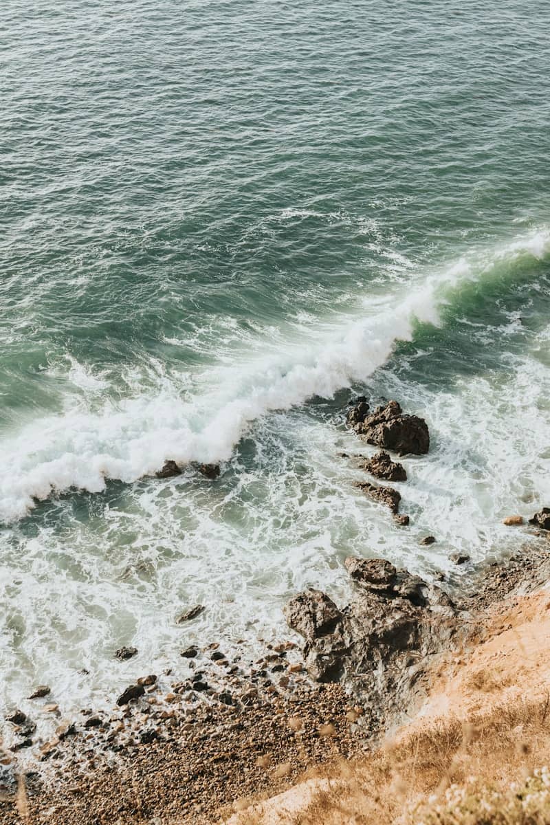 Green ocean waves crashing on a rocky shore.