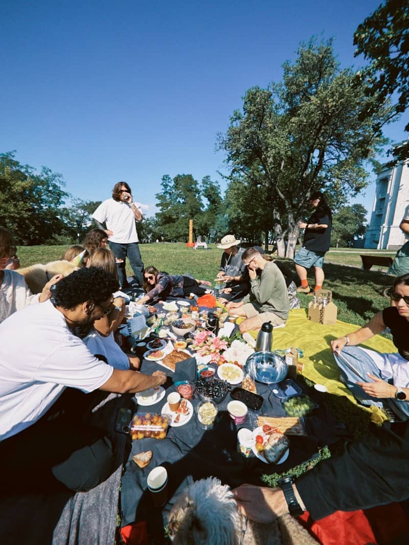 Friends enjoying a sunny outdoor picnic with food.