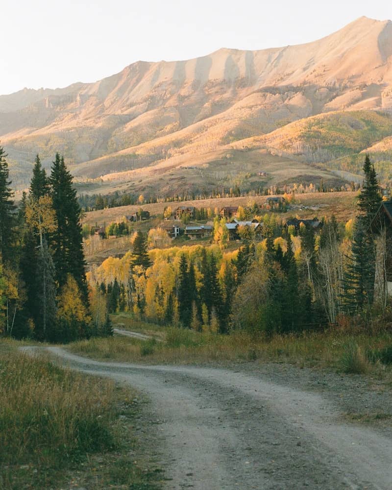 Dirt road leading to a village in autumn mountains.