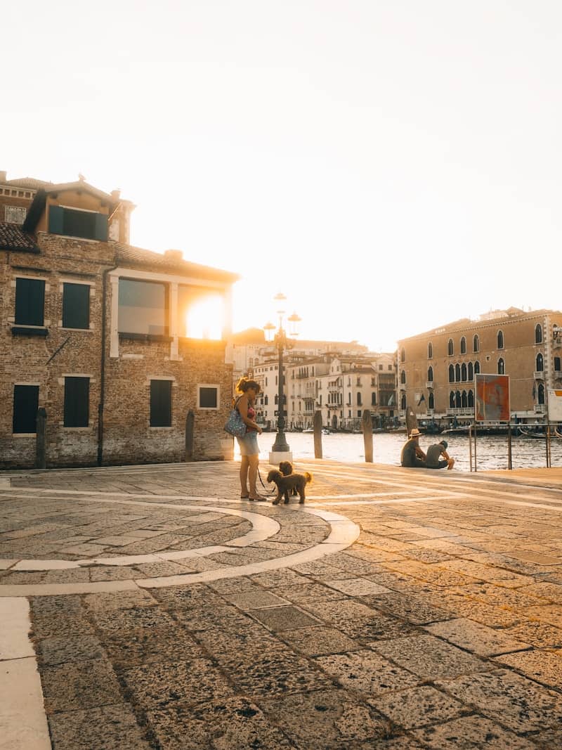 Woman with dog on paved square near canal