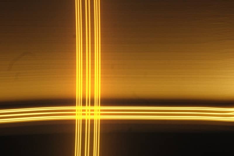Intersecting golden light trails create a luminous cross.
