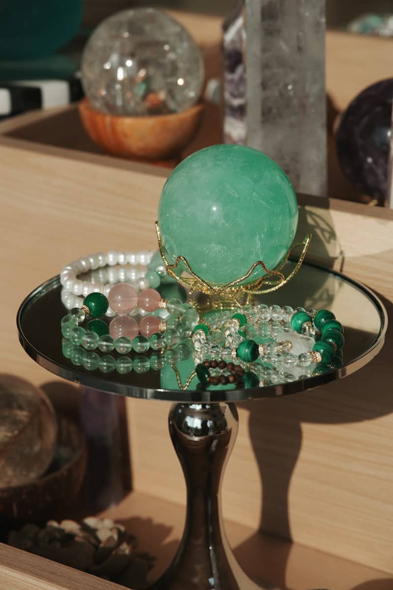 Green crystal ball with bracelets on mirrored stand