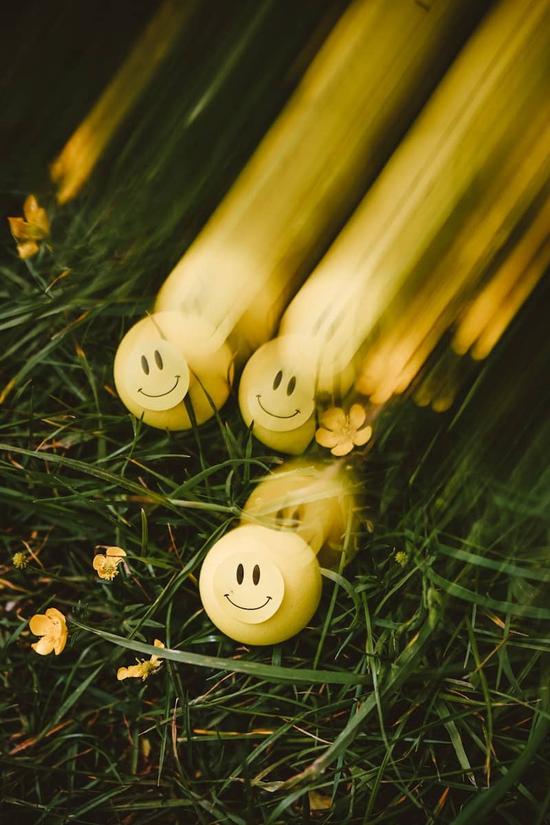 Yellow smiley balls rolling on green grass