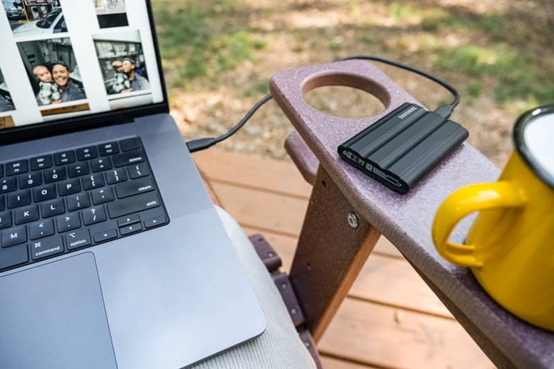 Laptop, external hard drive, and mug on chair