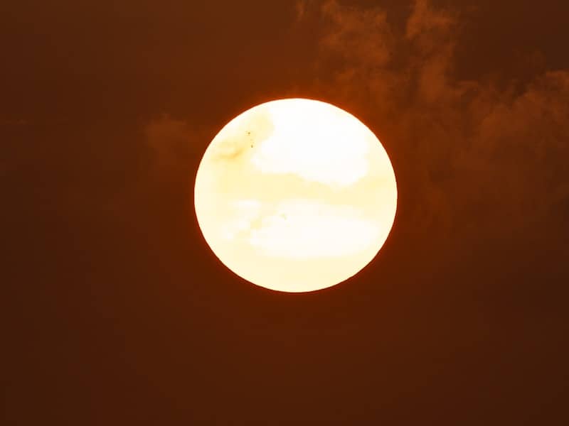 A glowing sun against a dark, cloudy, reddish sky.