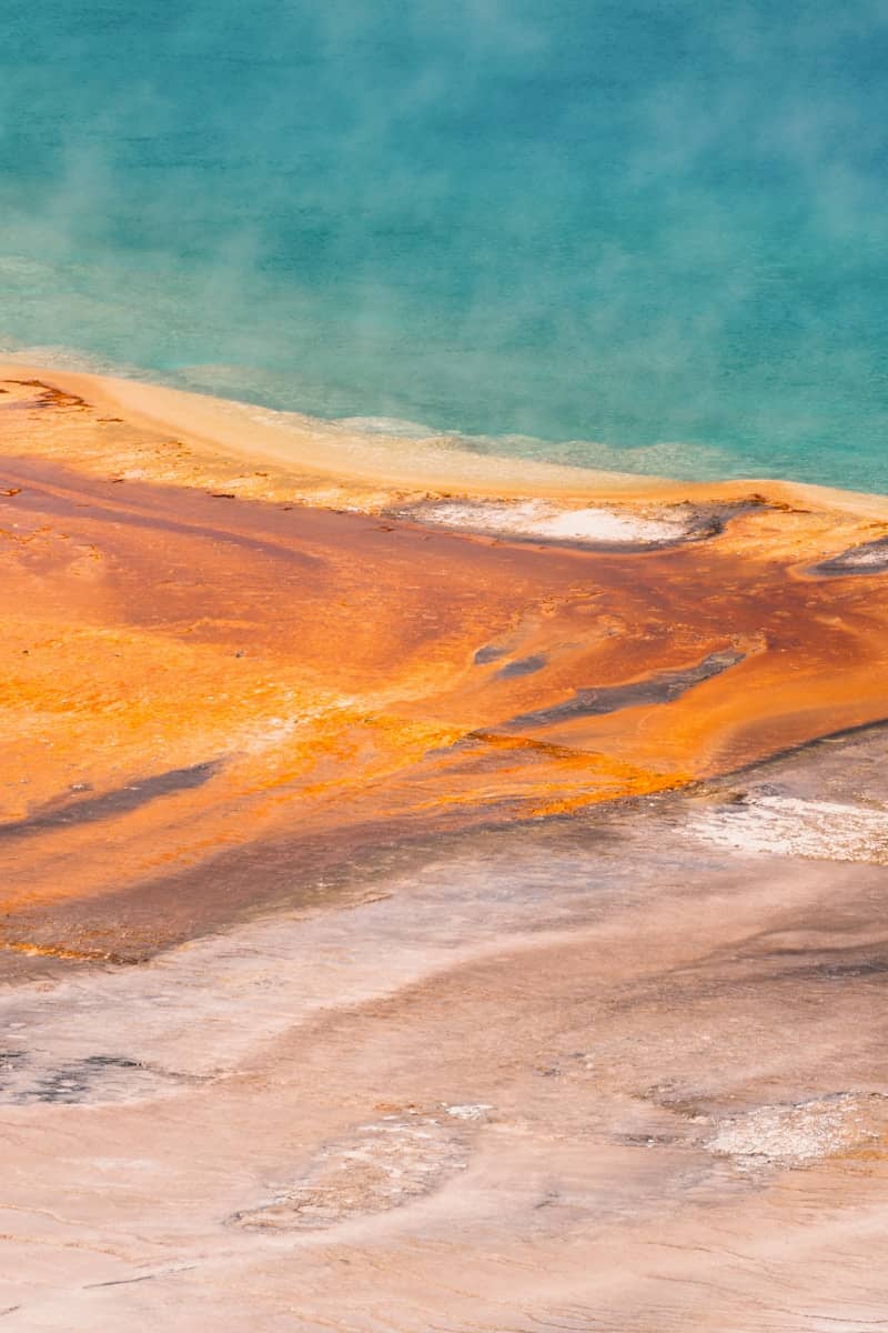 Colorful geothermal spring with turquoise water and orange mineral terraces.
