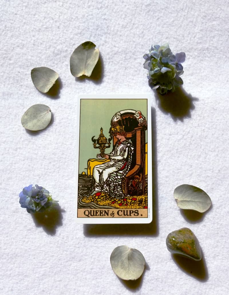 Queen of cups tarot card surrounded by petals.
