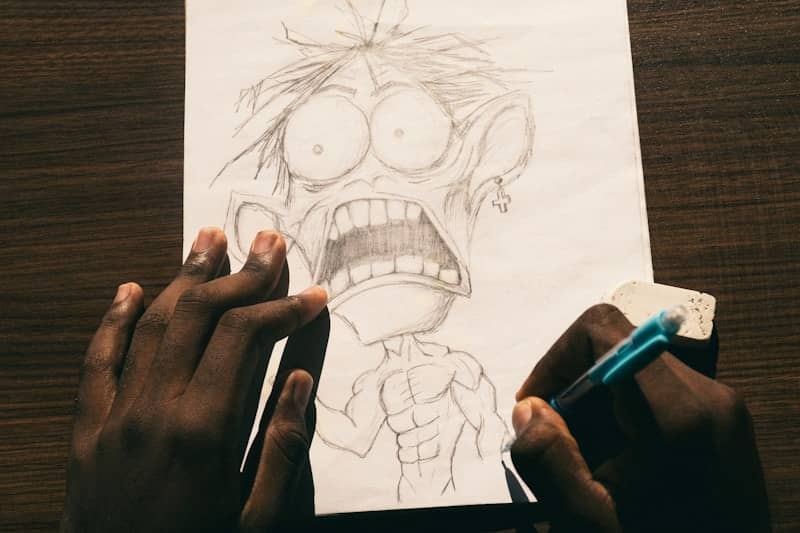 A person drawing a cartoon character with a large head on white paper