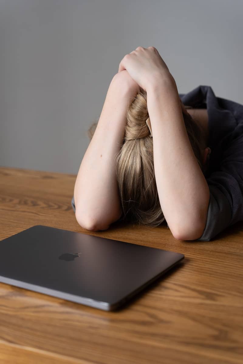 A person with head in hands next to a laptop
