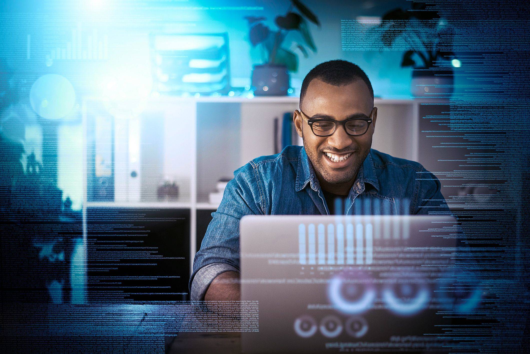 Man siting in front of comupter with data graphs floating