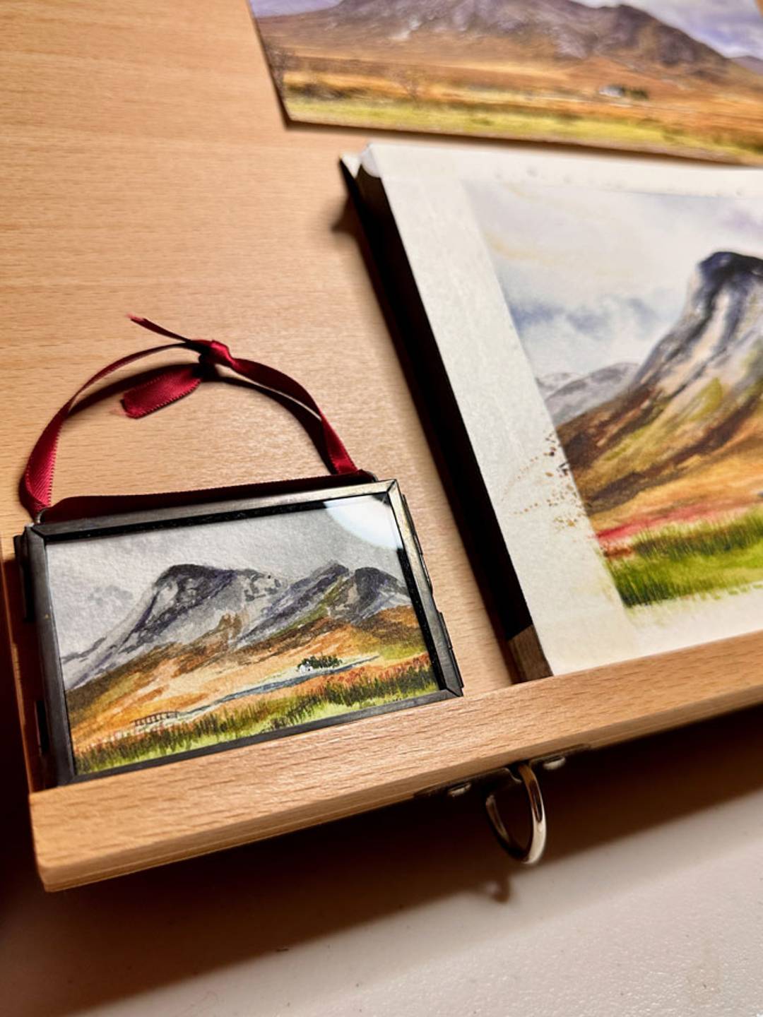 close up of a two by three in glass framed ornament holding a watercolor painting