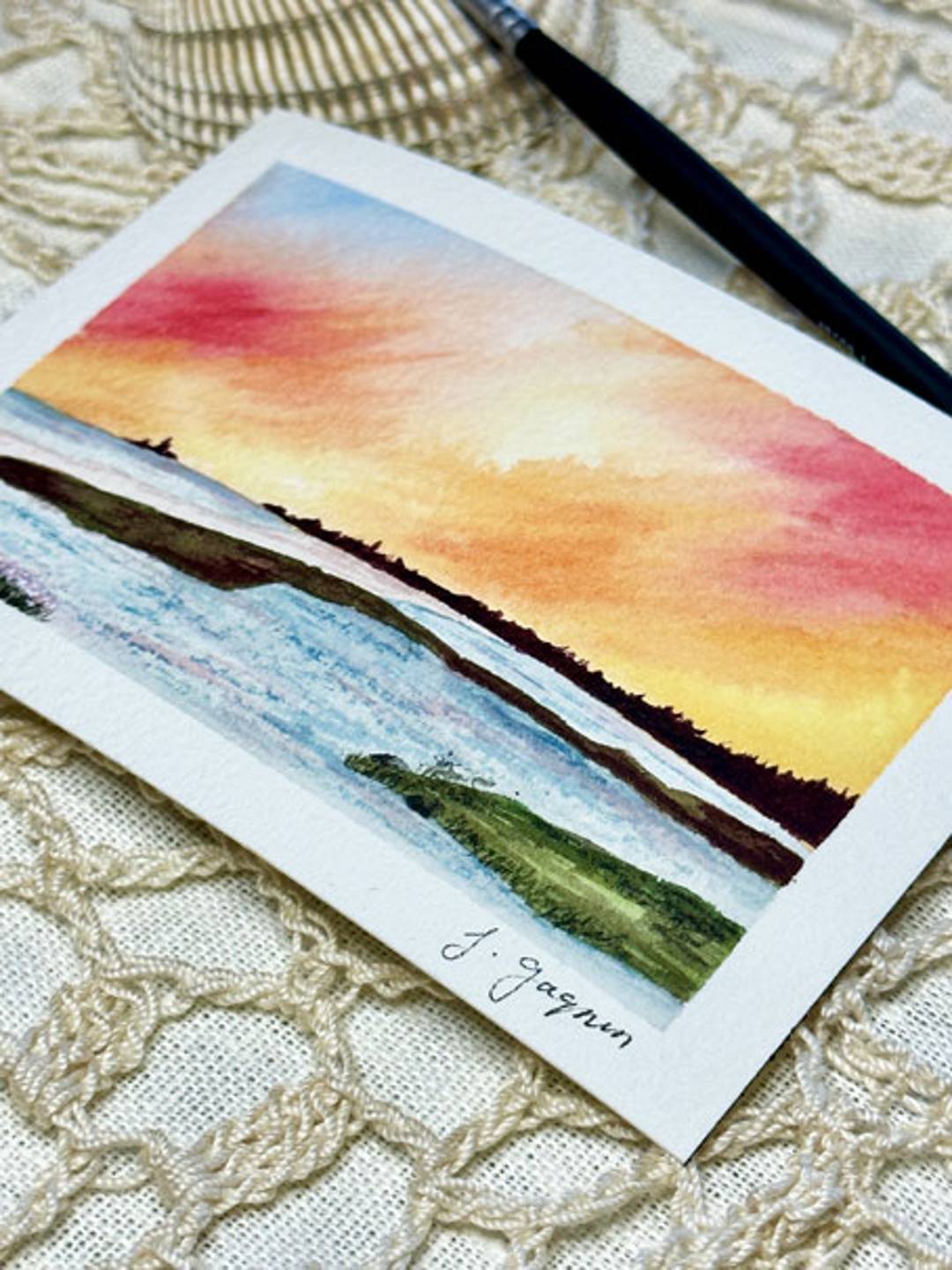 watercolor painting of where the beach meets the bay at sunset