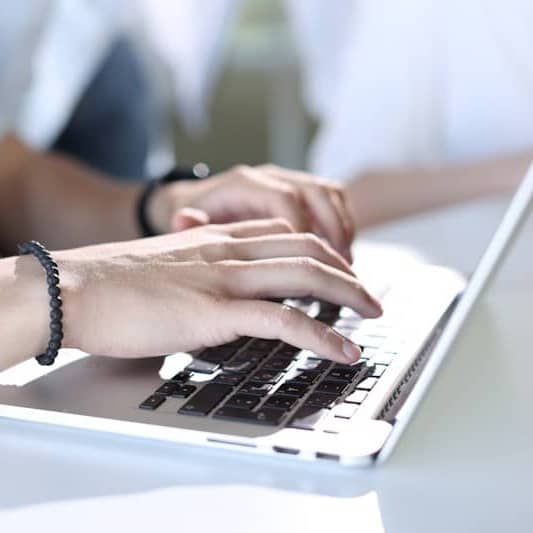 A person typing on a laptop on a table